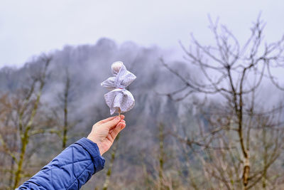 A woman's hand holds in her hand a small shrovetide doll against the background of nature