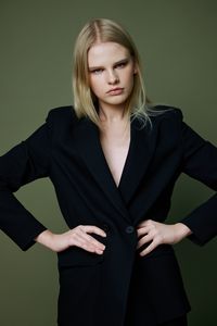 Portrait of young woman standing against gray background