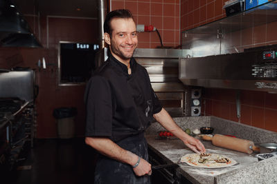 Pizza making process. male chef making authentic pizza in the pizzeria kitchen.