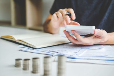 Midsection of man using mobile phone on table