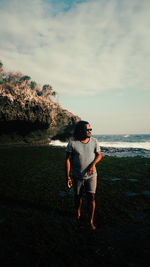 Rear view of woman standing on rock at beach