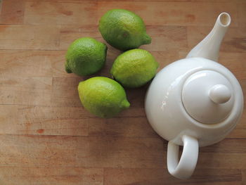 High angle view of limes by teapot on wooden table