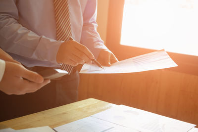 Cropped image of businessmen analyzing paperwork on table