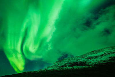 Low angle view of green mountain against sky at night