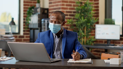 Man using laptop while sitting on table