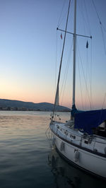 Sailboats moored in sea against clear sky during sunset