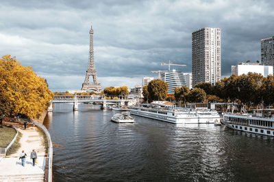 Buildings by river against cloudy sky