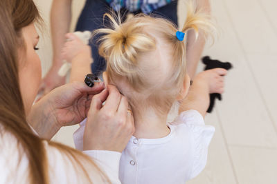 Close-up of mother helping daughter with hearing aid