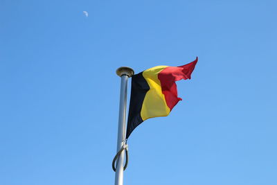 Low angle view of flag against clear blue sky