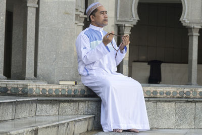 Man holding umbrella while sitting on staircase