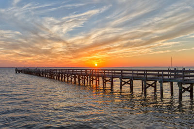 Pier over sea against sky during sunset