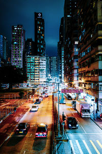 Traffic on city street amidst buildings at night