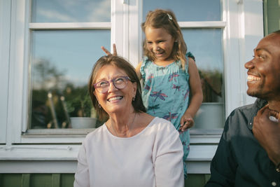 Happy multi-generation family against window at porch