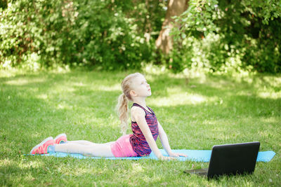 Rear view of woman using mobile phone in grass