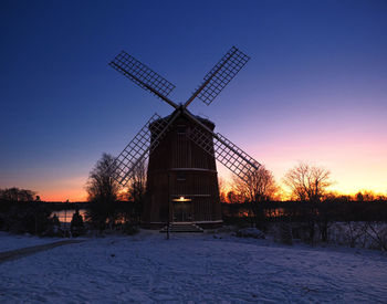 Traditional windmill against sky during winter