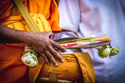 Midsection of person holding religious offerings