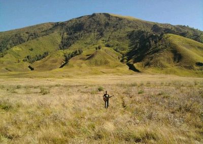 Man standing on field against mountain range