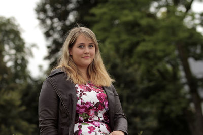 Beautiful young woman standing against trees