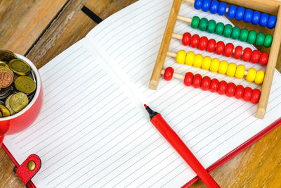 High angle view of colorful abacus with coins and book on wooden table