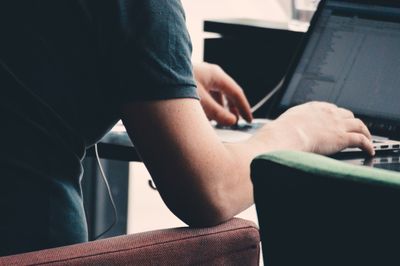 Midsection of man using mobile phone while sitting on table