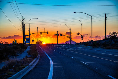 Road by city against sky during sunset