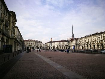 People walking on street in city against sky