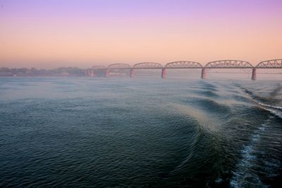 Bridge over sea against clear sky during sunset