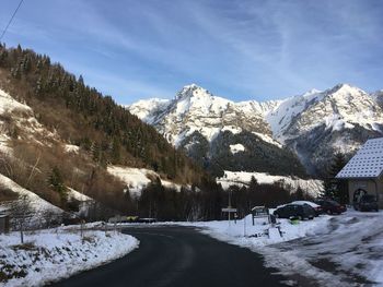 Snow covered road by houses against sky