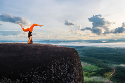 Man standing on rock by sea against sky