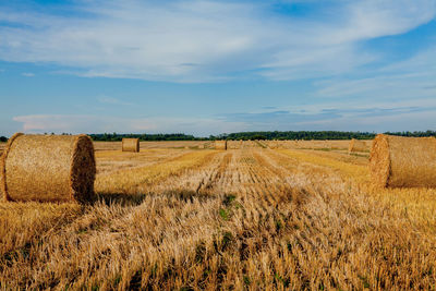 Hay bales on field against sky