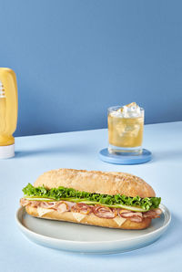 Appetizing sandwich with ham and fresh lettuce served on plate on table in cafeteria