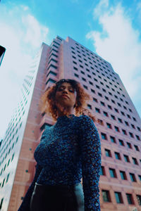 Low angle view of woman standing against building in city