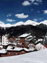 Snow covered houses by buildings against sky