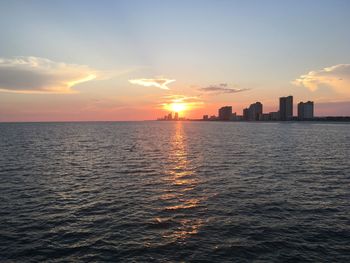 Scenic view of sea and buildings against sky during sunset