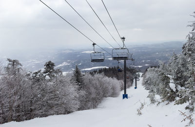 Overhead cable car over snow covered mountains against sky