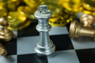 Close-up of chess pieces and coins on board