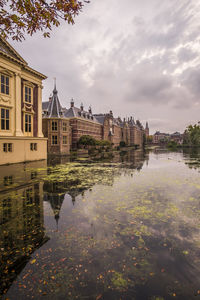 Arch bridge over lake by buildings against sky