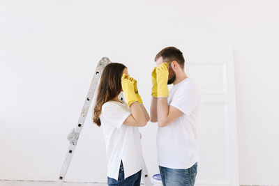 A young couple in love have moved into a new house and are making repairs painting white walls