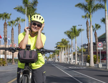Portrait of woman wearing helmet standing with bicycle on road