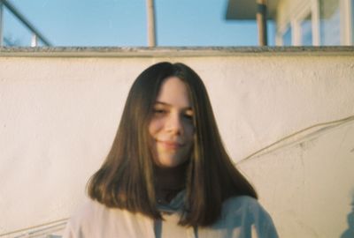 Portrait of beautiful young woman against wall