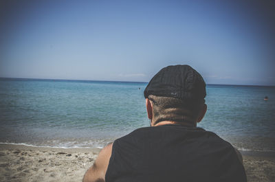 Rear view of man on beach against clear sky