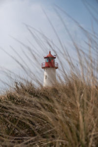 Lighthouse on field against sky