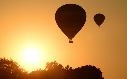Silhouette hot air balloons against sky during sunset