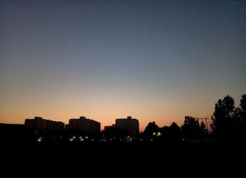 Silhouette buildings against clear sky during sunset