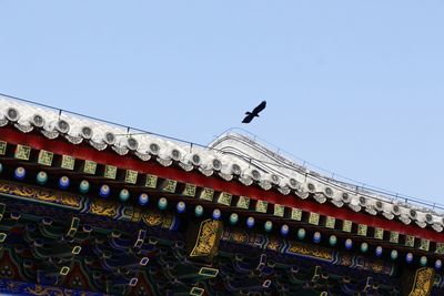 Low angle view of birds on roof against sky