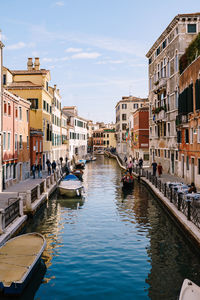 Canal amidst buildings in city against sky