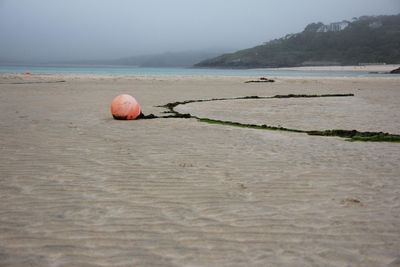 Buoy at sandy beach against sky