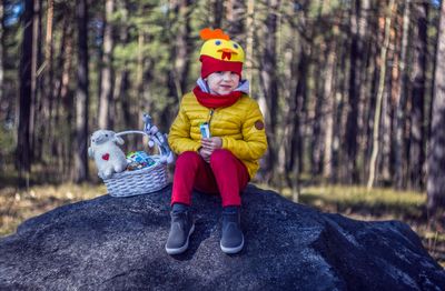 Full length portrait of smiling boy sitting in forest