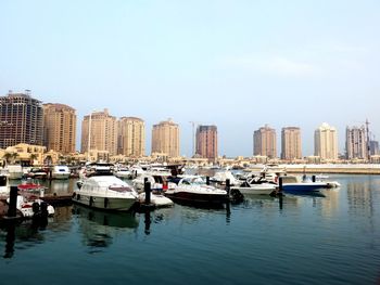 Boats moored in canal by buildings against clear sky