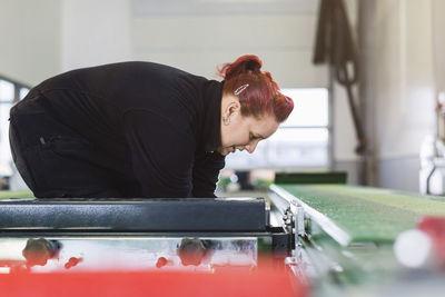 Side view of female mechanic using hydraulic lift in auto repair shop